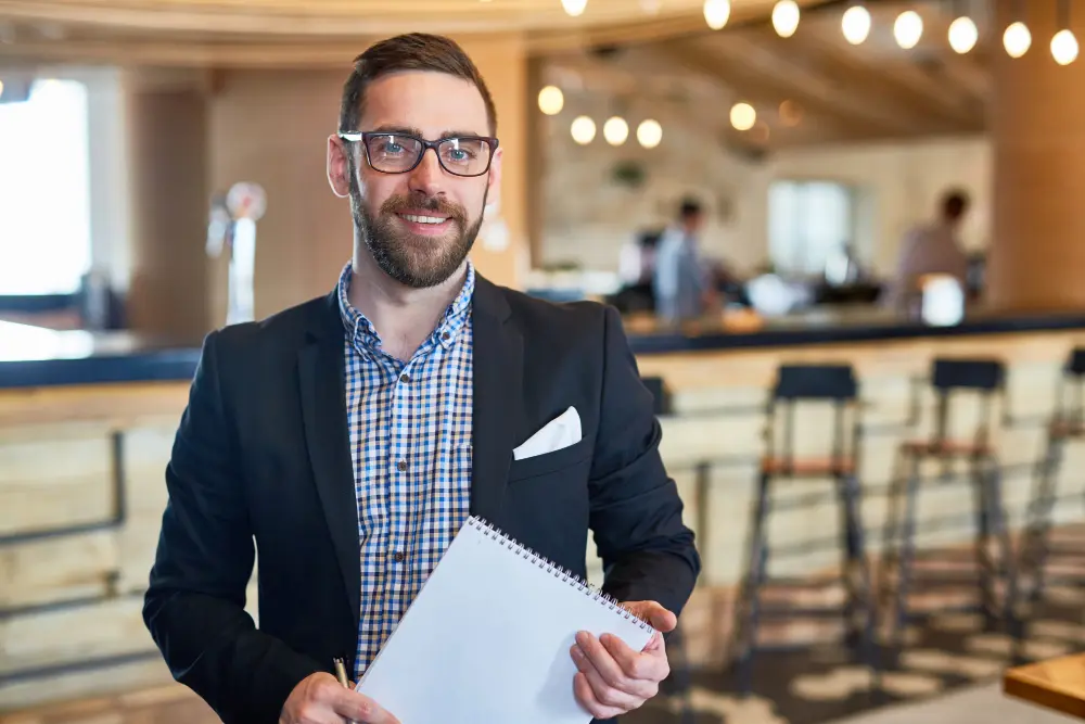 Homme souriant avec carnet dans un café moderne
