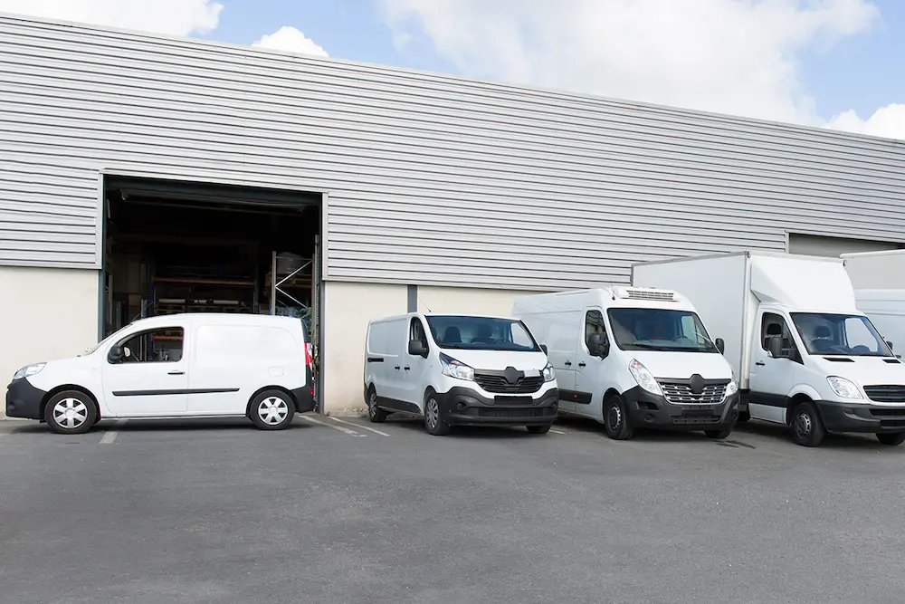 Fourgonnettes blanches garées devant un entrepôt