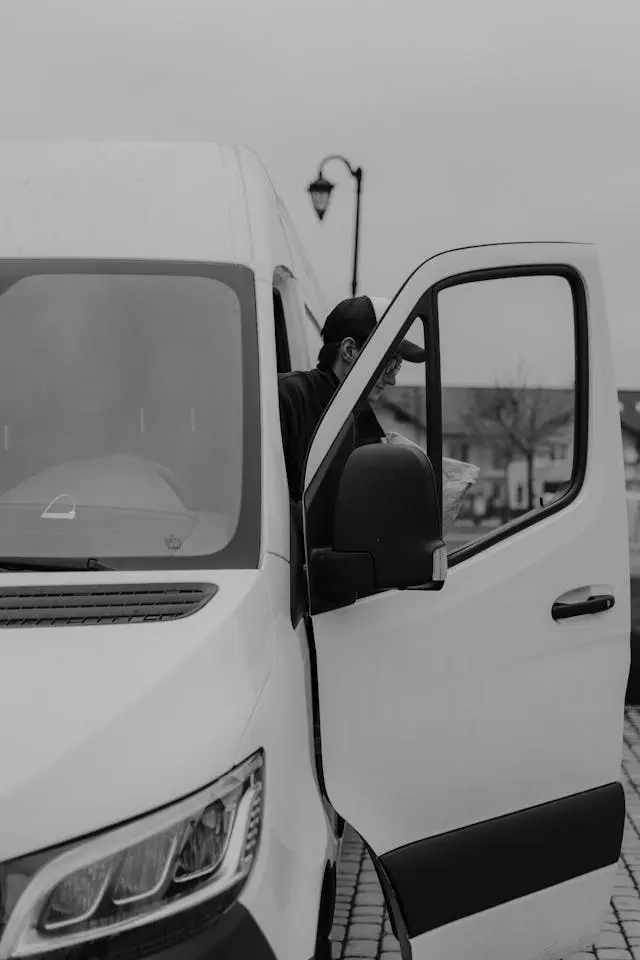 Livreur ouvrant la porte d’un utilitaire blanc
